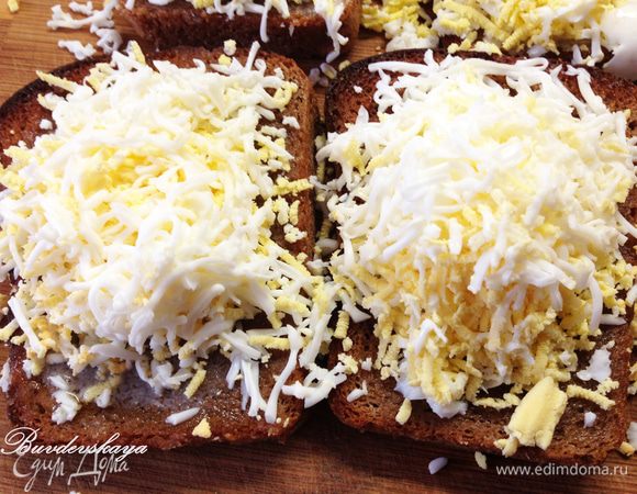 На мелкой терке натереть пол яйца на каждый бутерброд. Слегка посолить.