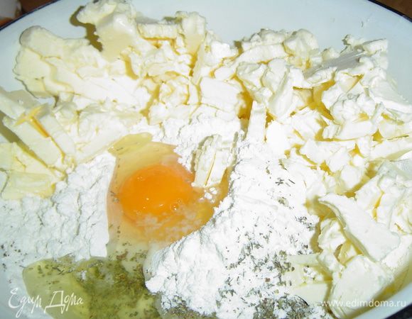 Начинаем с приготовления теста, для этого порубим охлажденное масло, добавим яйцо, соль, муку, итальянские травы и замесим тесто.