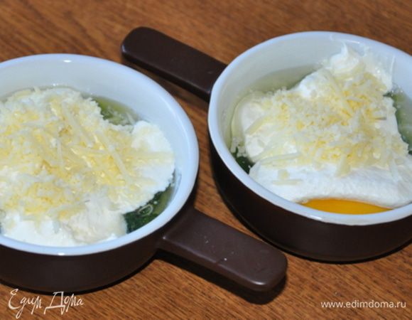 На яйцо аккуратно выложить по 2-3 ст.л. сливок и посыпать пармезаном.
