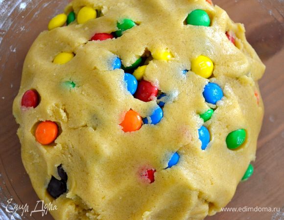 Помогая себе руками, смешайте тесто с конфетками. Включите духовку на 170°C.