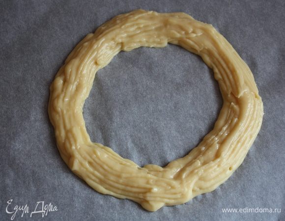 Даем чуть остыть и набираем тесто в кондитерский мешок. разогреваем духовку до 200 градусов. На пергаменте с обратной стороны рисуем круг диаметром 20 см. Теста и крема хватает на 2 таких кольца или 12 маленьких колечек. С помощью кондитерского шприца или мешка наносим тесто,один ряд внутри обведенного круга,следующий ряд внутри -первого,а третий по центру наверху первых) Берем вилочку,обмакиваем ее в яйцо взбитое с водой и проходимся по тесту аккуратно.