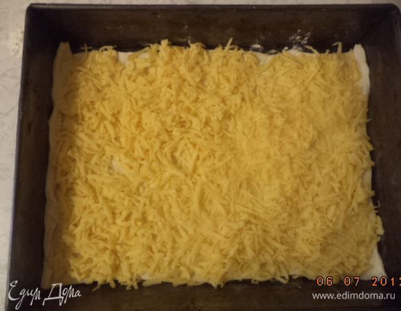 Противень смазать сливочным маслом, выложить один пласт теста. На тесто равномерно выложить сыр и кусочки сливочного масла. Накрыть вторым пластом теста.