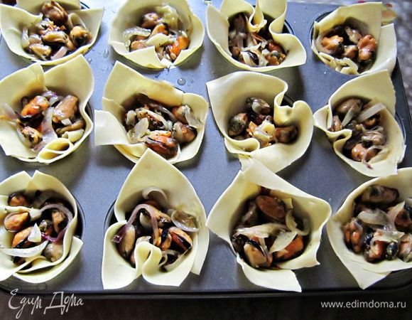 В каждую формочку (или, как у меня, ячейку) выложить лист для лазаньи так, чтобы сформировались корзиночки. Начинку распределить по формочкам, полить взбитыми с яйцом сливками 