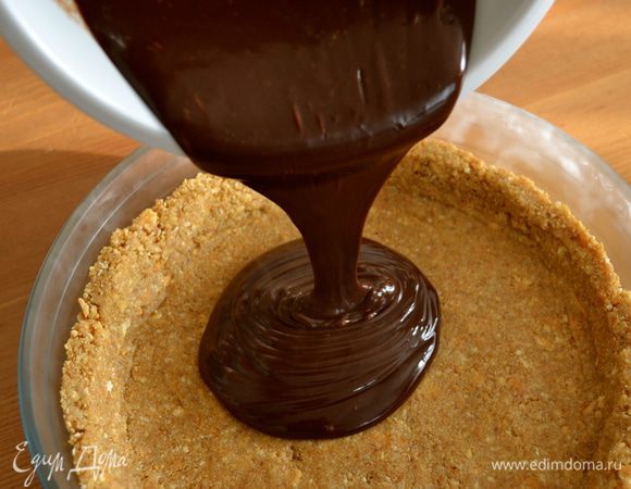 Достать из холодильника форму с коржом и выложить на корж шоколадную массу.