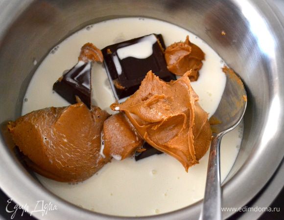 Тем временем приготовить следующий слой для пая на арахисовом масле (пасте). Для этого в небольшую кастрюльку положить шоколад, арахисовую пасту и половину стакана сливок. Поставить на водяную баню и постоянно помешивать, пока шоколад и арахисовая паста полностью не растворятся и не перемешаются в однородный крем.     