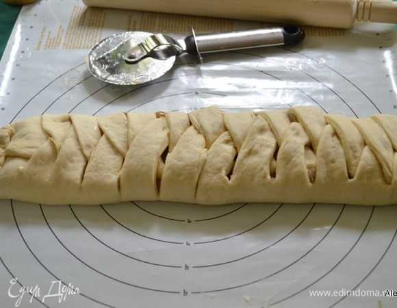 Теперь внахлест сначала слева ,затем справа накладываем полоски теста.
Соединяем и сворачиваем концы снизу и сверху. Промазываем сливками и посыпаем сверху крупным сахарным песком.