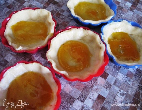 Из большей части теста выдавливаем кружки,12 штук, большего диаметра, чем формочки. Укладываем в формочки тесто, и на дно кладем по чайной ложечке повидла или густого джема.