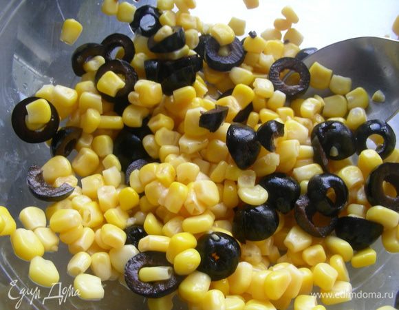 Оливки нарежьте колечками и выложите в салатницу. Добавьте кукурузу, рис и грибы.