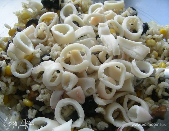 Кальмары также нарежьте колечками и добавьте в салат. Перемешайте и заправьте оливковым маслом, посолите, поперчите по вкусу, добавьте немного зелени.