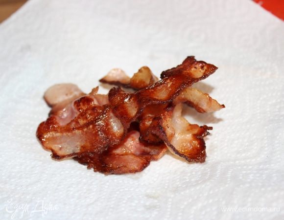 Пластинки бекона обжарить на сухой раскалённой сковороде и выложить их на салфетку, чтоб стекал лишний жир.
