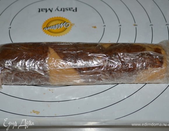 Затем верхнюю пленку снимаем и начинаем с узкой стороны сворачивать рулетом. Закроем пленкой нижней и в морозильник на час или более.