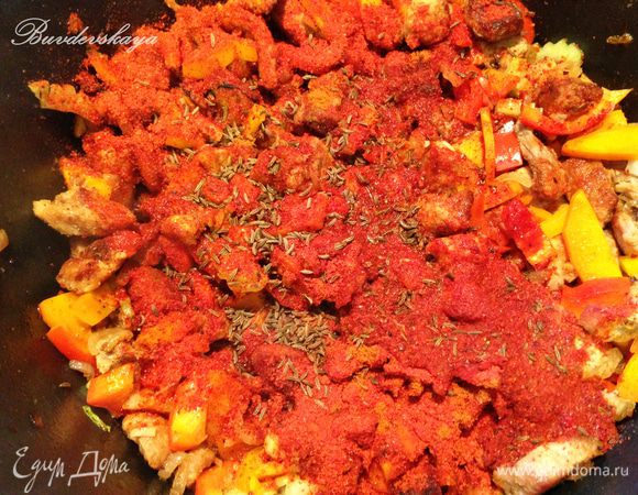 Нарезанные перцы, сельдерей и чили выложить к мясу. Добавить паприку, сухой чили и тмин. Залить стаканом  воды и тушить на небольшом огне минут 30, постепенно добавляя еще 800 мл воды.