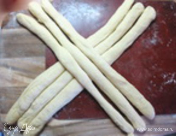 Подошедшее тесто обмять и разделить на 6 равных частей. Из каждой части раскатать жгут длиной 30-35 см. Выложить жгуты крестом.
