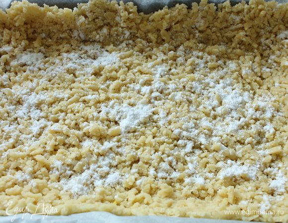 Форму для выпечки выстелить пергаментом.Тесто из холодильника натереть на крупной терке,распределить равномерно,сформовать бортик,подпылить крахмалом.