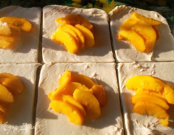 Тесто разрезать на несколько квадратов (у меня вышло 6). На каждый выложить 1 ч л сахара и дольки персиков.