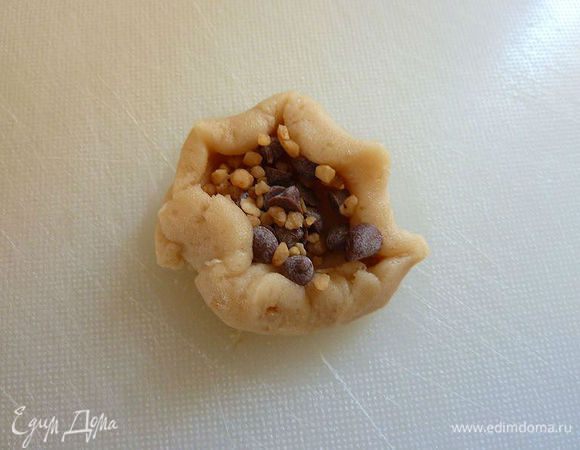 В центре каждого круга положить не много начинки .Закройте тесто вокруг и  сформировать шарик между  руками . Осторожно, чтобы не было дырочек  и шоколад не вылизал из теста.  
