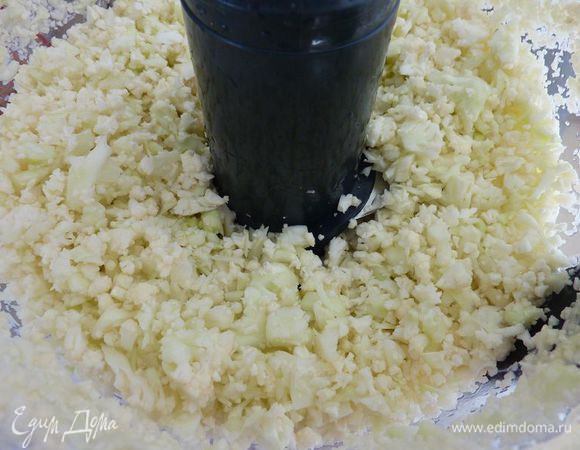 Разогреть духовку на 180 градусов. Промыть капусту и разобрать  на мелкие кусочки (размером примерно 2-3 см). Переложить капусту в кухонный комбайн и короткими импульсами, измельчить мелко (так же можно нарезать лук). Можете нарезать цветную капусту всё мелко ножом. 