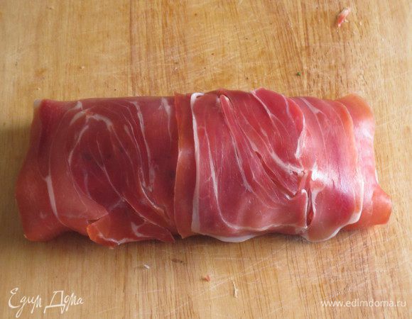 .....обернуть ломтиками ветчины, обвязать кулинарной ниткой и выложить на противень с фольгой. Запекать в разогретой до 190 °С духовке 45 минут.