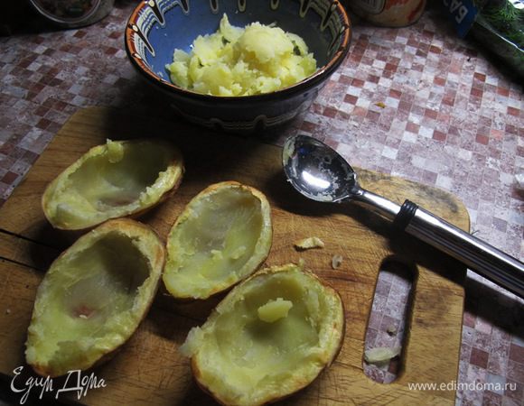 Когда картофель испечется, немного охладить его, вынуть из фольги. Аккуратно, ложкой извлечь мякоть, переложить в мисочку и смешать со сметаной и половиной сыра. 