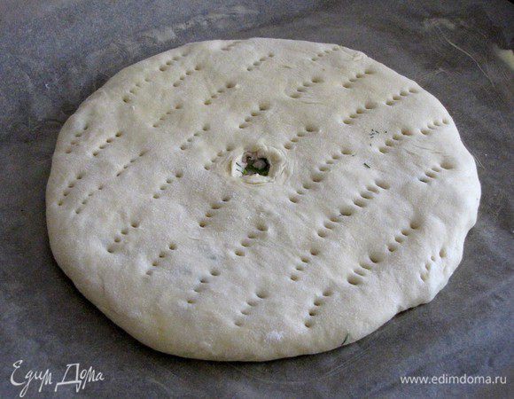 Разровнять, перевернуть и раскатать скалкой до ровного и плоского круга. Пирог перенести на противень, застеленный пекарской бумагой и смазанной маслом. В середине сделать маленькое отверстие для выхода пара. Пирог можно наколоть вилкой, не затрагивая дно.