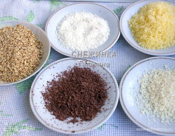 Далее мы будем обваливать каждый шарик в разной обсыпке. Для этого подготовим кокосовую стружку, стружку из тёмного и белого шоколада (я её сделала при помощи овощечистки), измельчённые грецкие орехи, измельчённые кукурузные палочки.