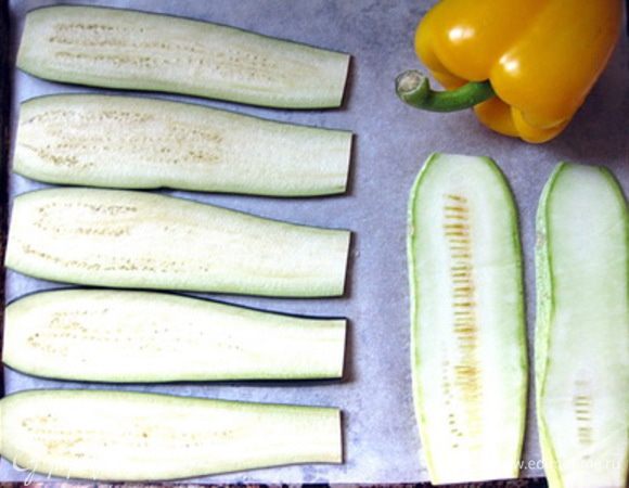 Баклажаны и кабачок нарезать тонкими пластинами вдоль, выложить вместе с целым перцем на застеленный бумагой противень, смазать овощи оливковым маслом.
