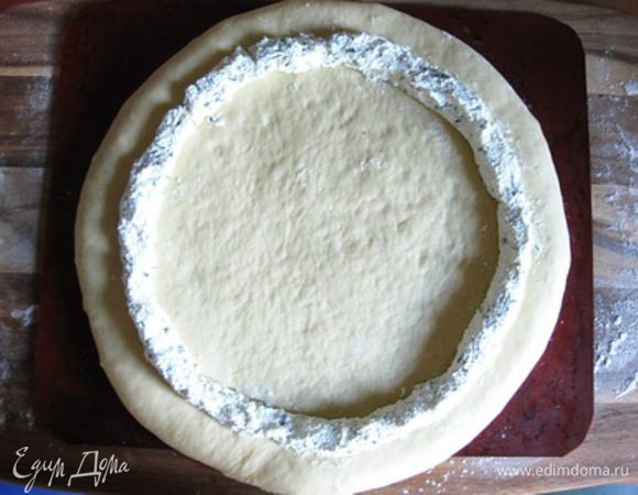 Формовка пирога
Подошедшее тесто еще раз вымесить и раскатать в круг (лучше это сразу делать на противне, застеленным бумагой или силиконовым ковриком).
Выложить по кругу сырную начинку, отступив от края пару сантиметров.