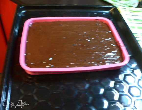 Поставить прямоугольную форму на противень и влить в неё шоколадное тесто. Распределить лопаткой массу ровным слоем. Выпекать 30-35 минут, пока корж не покроется блестящей корочкой и не будет плотным при надавливании пальцем в центре.