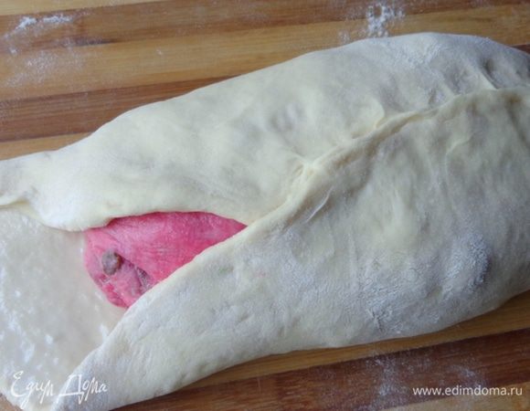 Раскатать белое тесто, смазать поверхность пласта и красный колобок молоком и обернуть красное тесто белым. Защипать края.