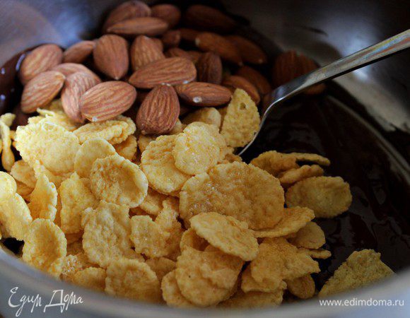 В горячий растопленный шоколад всыпать  хлопья и орехи.