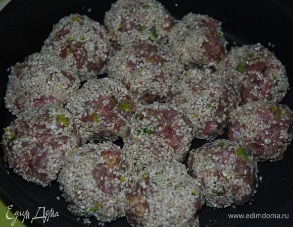 Смоченными в холодной воде руками сформировать из фарша одинаковые колобки-шарики и запанировать их в кунжуте, далее уложить их в форму смазанную маслом, в которой будете запекать блюдо