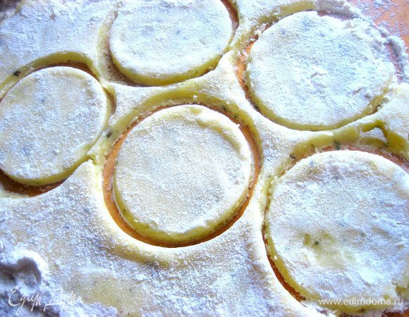 Раскатываем,не сильно прижимая,и вырезаем стаканом кружки,макая края стакана в муку.