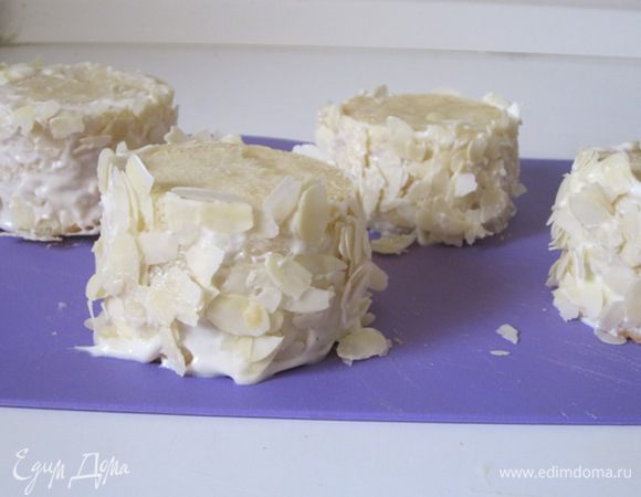 Смазать бока кремом и обвалять в лепестках миндаля.