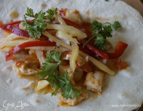 Теперь нужно собрать лепешку: овощи, затем курицу и зелень, свернуть трубочкой.