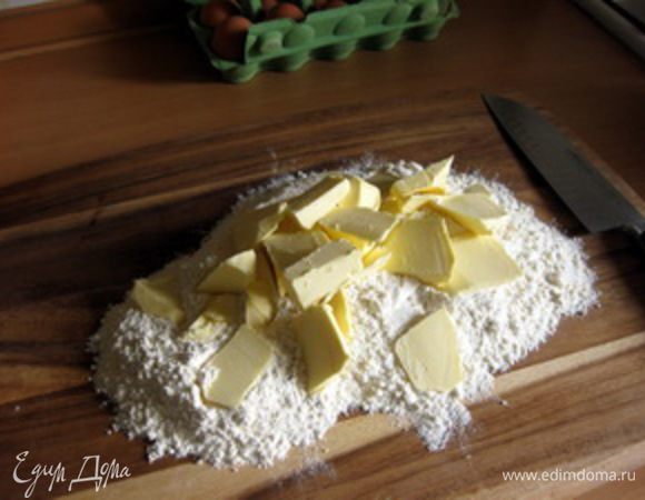 Тесто. Муку высыпать на большую разделочную доску, сверху нарезать крупными кусками маргарин или масло.