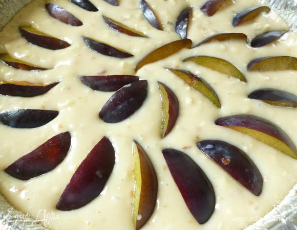 У слив удалить косточки, нарезать их дольками и распределить по всей поверхности пирога.