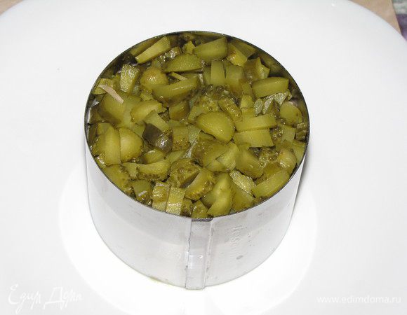 Следующий слой - соленые огурчики. Чтобы салат держал форму, все слои немного утрамбовываем.