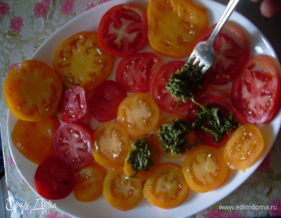 Нарезать помидоры кружочками и разложить на плоском блюде. На каждый кусочек сверху добавить немного песто.