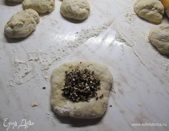 Тесто выложить на разделочную доску, припыленную мукой, слегка обмять и  разделить на 8 шариков. В формочки для кексов можно положить бумажные стаканчики для маффинов. Шарик слегка раскатать, положить начинку.