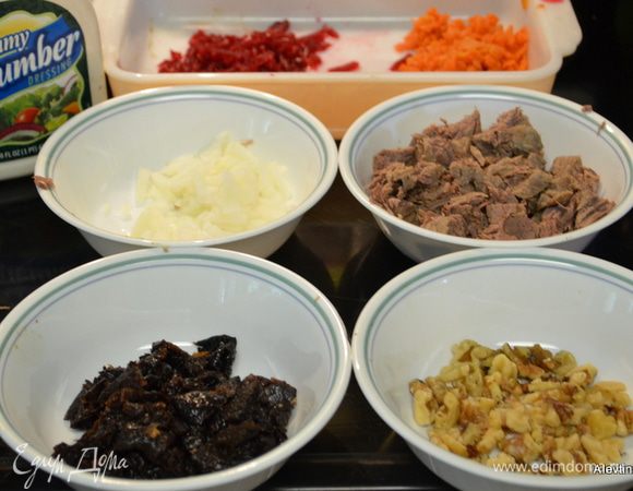 Говядину отварить, остудить и порезать на кусочки. Лук репчатый порубить мелко, морковь отварить и натереть на крупной терке, так же со свеклой. Чернослив, если жесткий, отмочить, затем очистить от косточек и нарезать мелко. Грецкие орехи очистить, порубить.