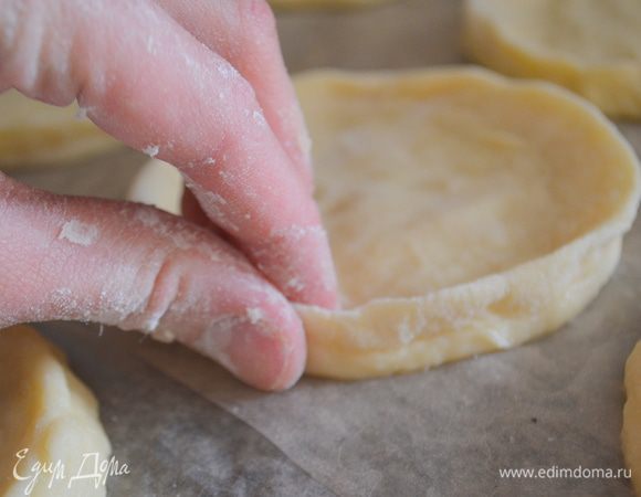 Заготовки перенести на противень, застеленный пергаментом или ковриком, и у каждого кружка сформировать бортики. Как бы защипнуть края.