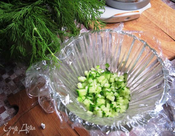 Форму для салата выстелить пищевой пленкой. Мелко нарезать огурец. Креветки проварить 2 минуты в кипящей соленой воде, добавив пару веточек укропа.