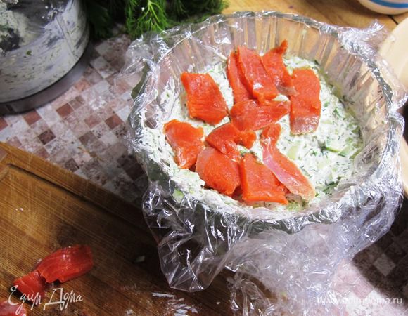 Выкладываем слои в форму. Нижний - паста из сыра с зеленью. Далее огурец, заправка, креветки, заправка, огурец, сырная паста, лосось.