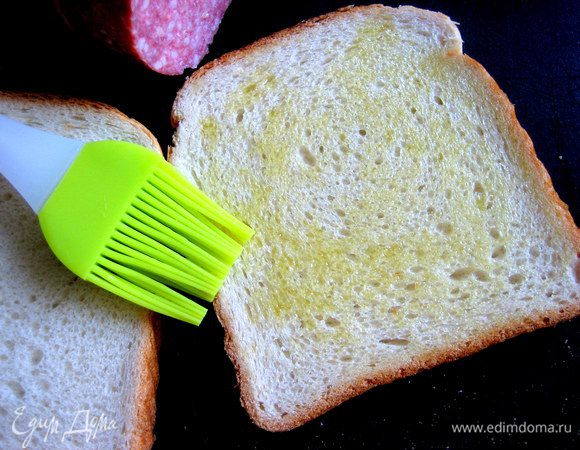 Нижний ломоть хлеба промазать оливковым маслом при помощи новенькой силиконовой кисточки...