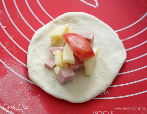 Подошедшее тесто вымесить, разделить на 12-14 частей, сделать шарик и раскатать. На него выложить начинку.