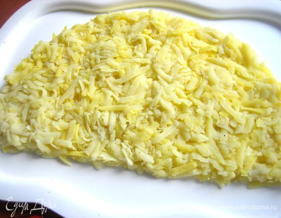 На плоском блюде ровным слоем выкладываем картофель и сразу формируем при помощи ножа полукруг.