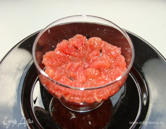 Грейпфрут очистить от пленочек, мелко порезать и выложить нижним слоем в порционные креманки.