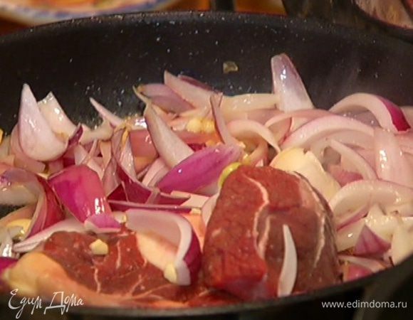 В сковороду с мясом добавить лук и чеснок и готовить, пока они не зазолотятся.