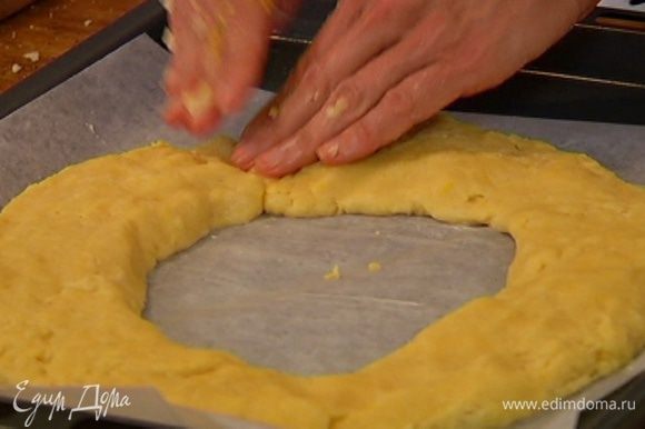 Противень выстелить бумагой для выпечки, смазать ее оставшимся сливочным маслом и выложить тесто, сделав из каждой колбаски полукруг и соединив их в кольцо.