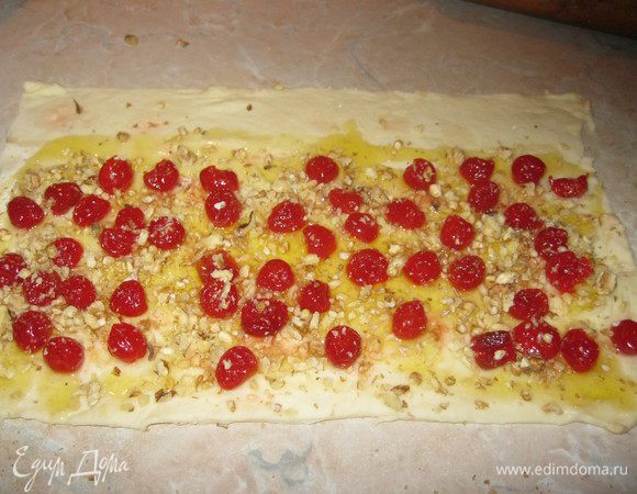  Один полил медом, оставив с длинной стороны полоску в два пальца. Выложил на него вишню и посыпал молотым грецким орехом. Потом скатал в рулет и нарезал на дюжину частей. Готовые рулетики выложил на поддон, застелив его пекарской бумагой. Так же поступил со второй половиной теста, положив в него изюм.  Из обрезков сделал булочки ассорти. Остатки изюма смешал с вишней. Поддон с рулетиками накрыл полотенцем и стал дожидаться гостей.